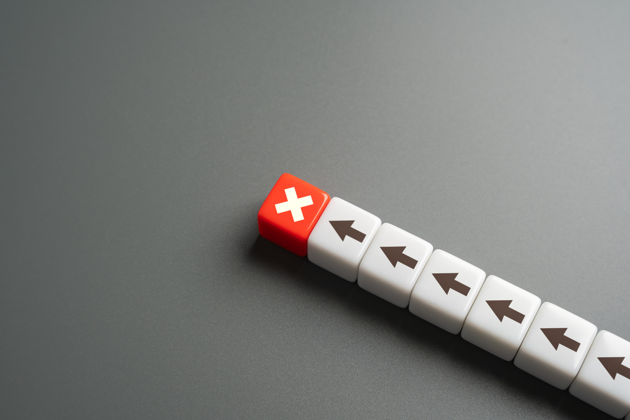 a line of white dice with black arrows on them and one red die with a white "x" at the top