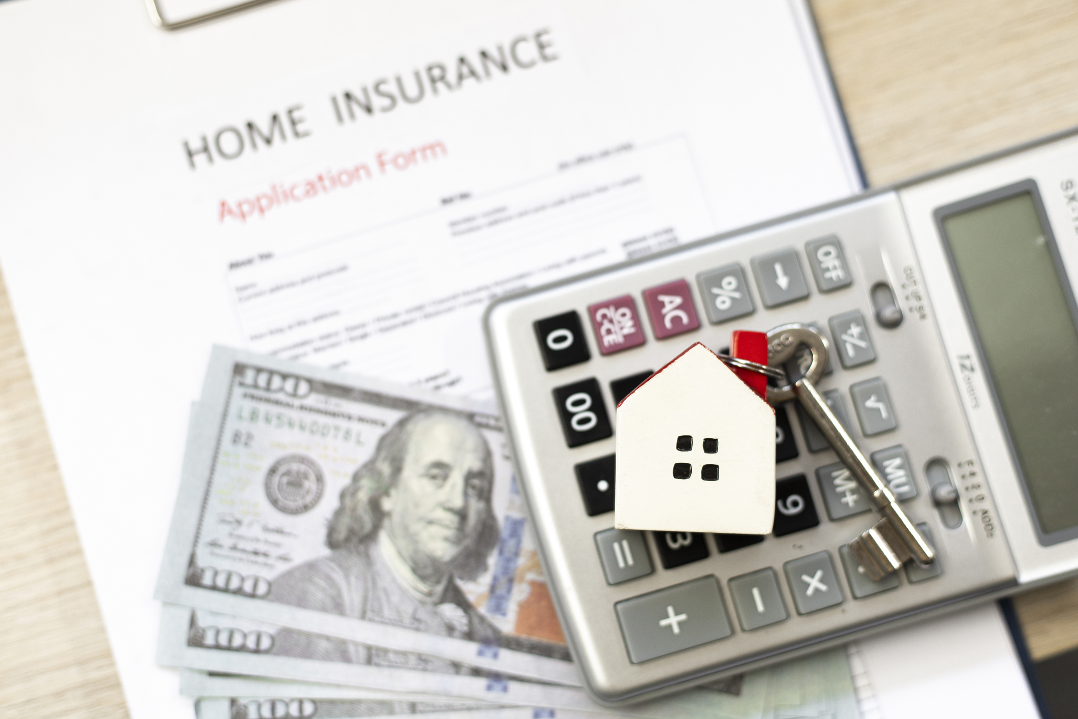Home insurance application form, calculator, and money on the desk. 