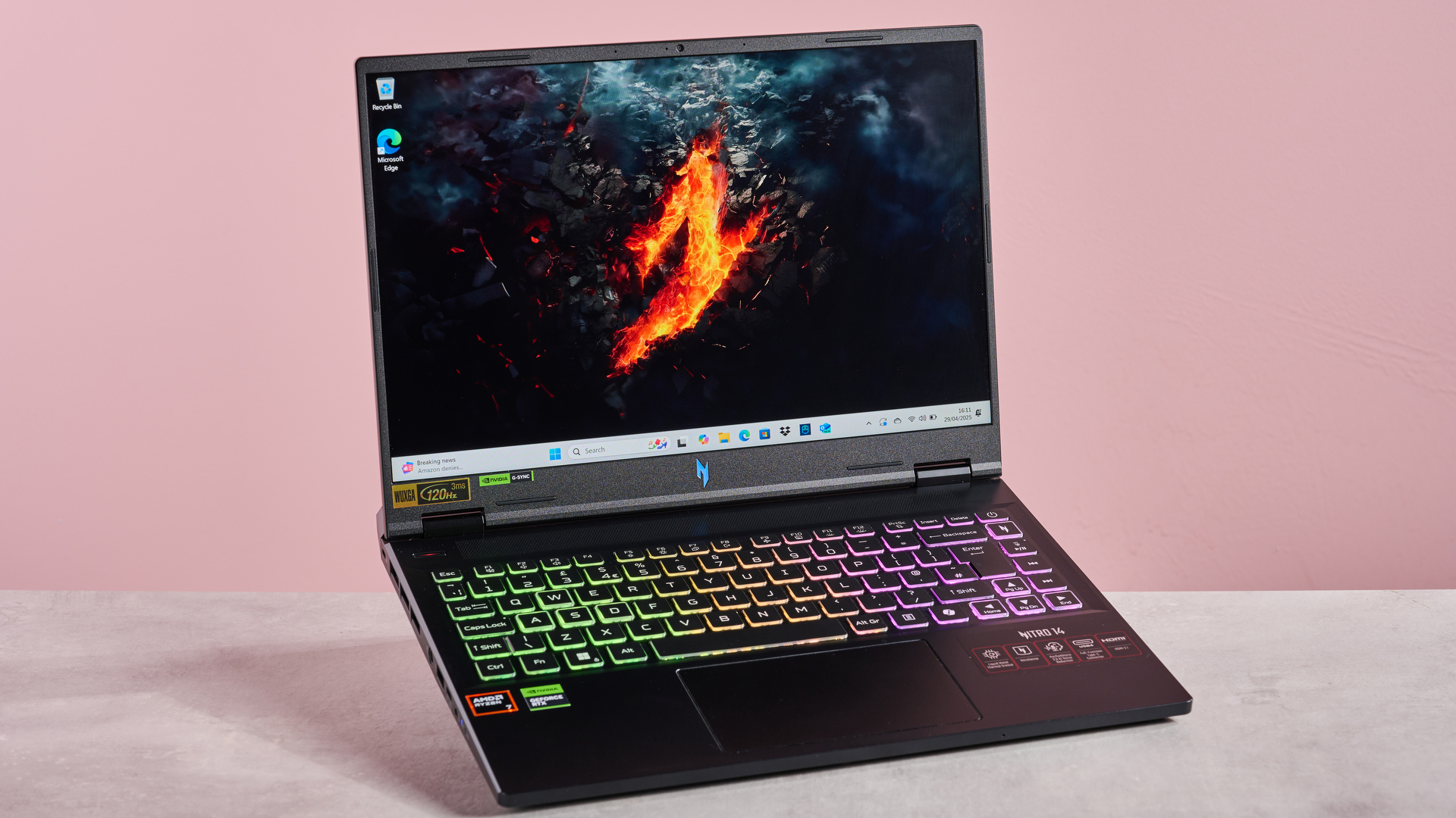 The Acer Nitro 14 compact gaming laptop photographed on a coral background.
