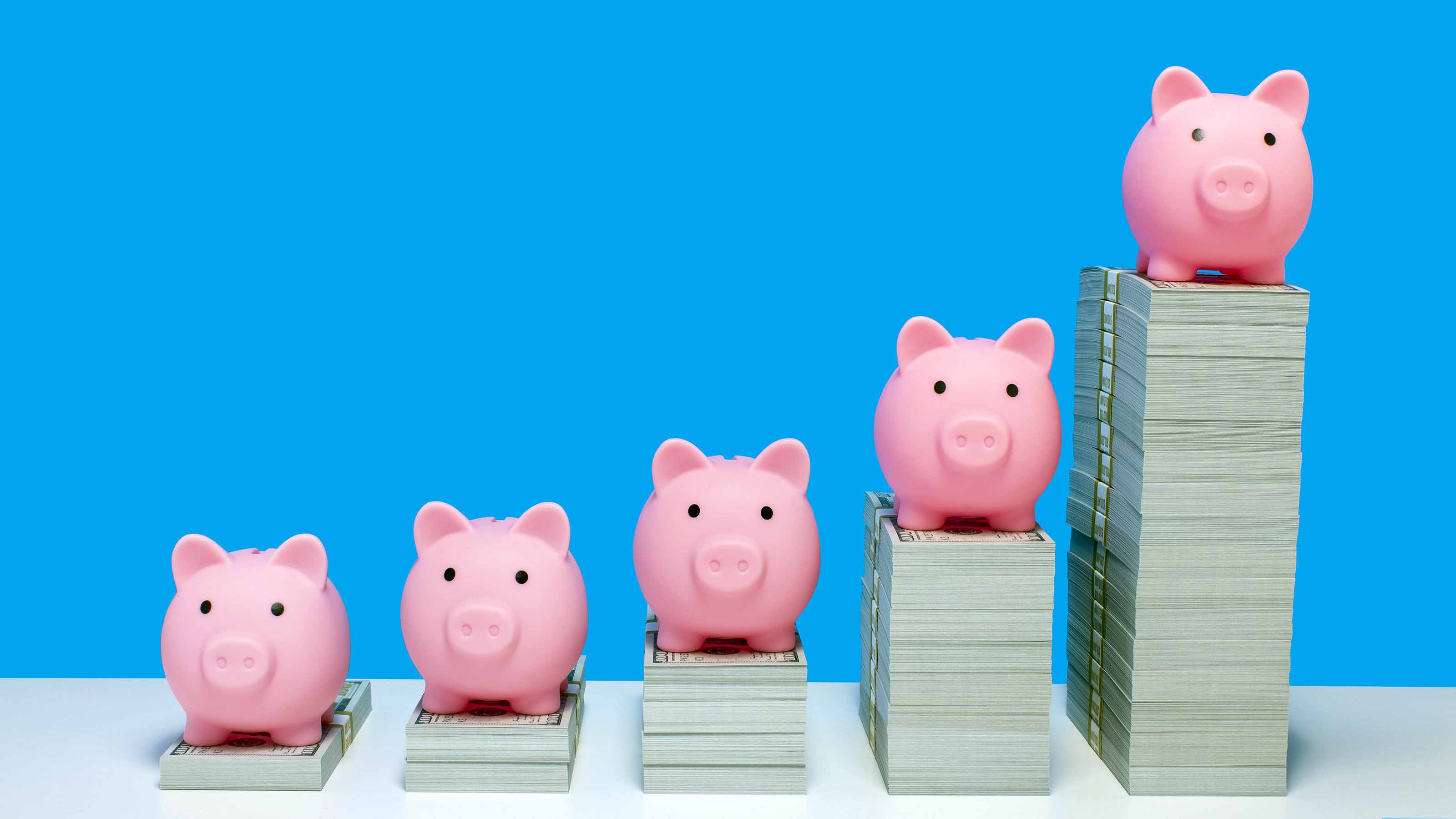 Stacks of cash that get increasingly bigger, indicating growth, with piggy banks on top of each stack.