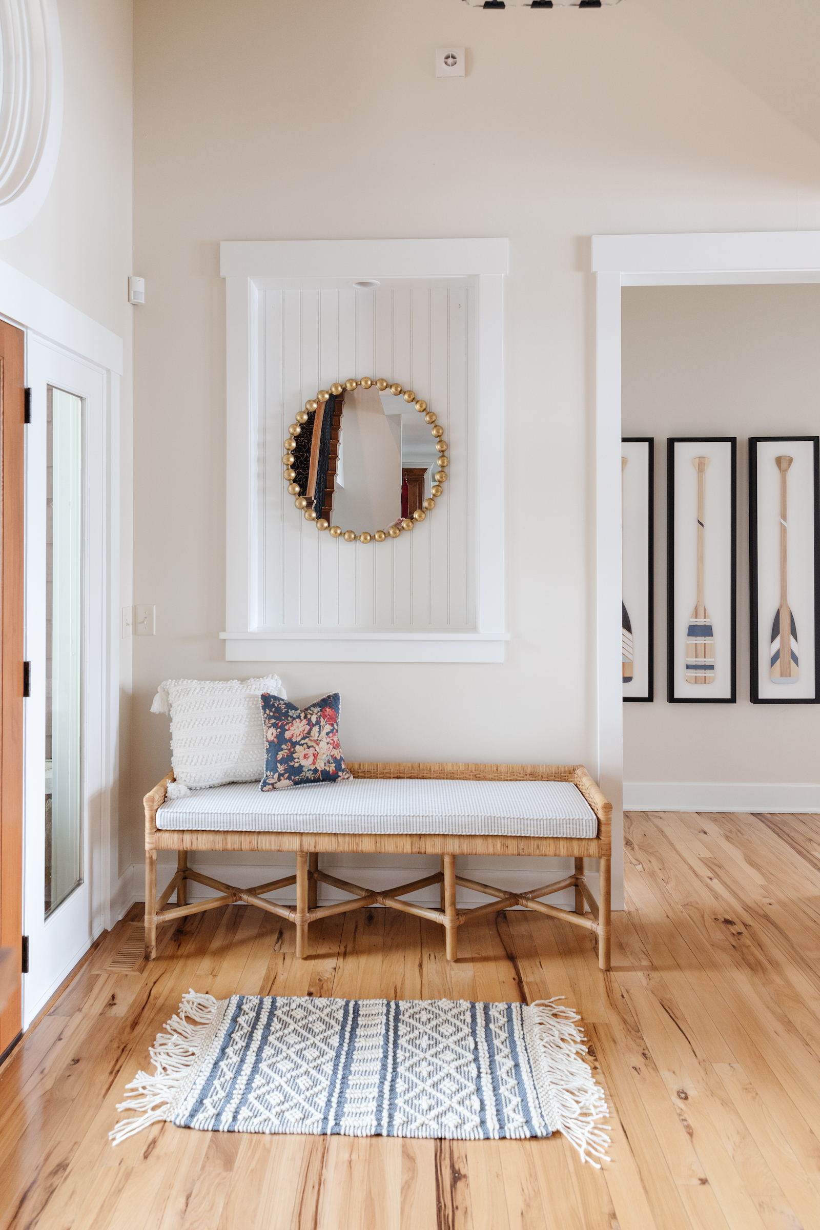 hallway with wooden floor and blue and white stripe rug gold mirror and oar artwork