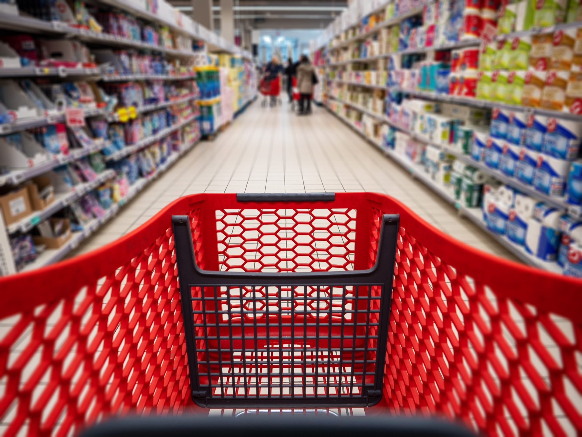 Personal perspective of a shopper pushing shopping cart along aisle while shopping in a supermarket.