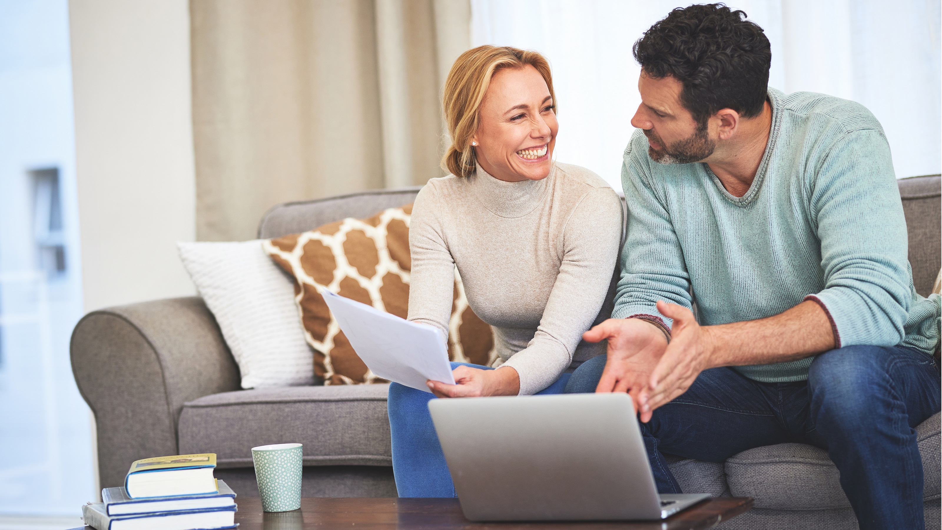 A couple sitting on the sofa work on financial planning.