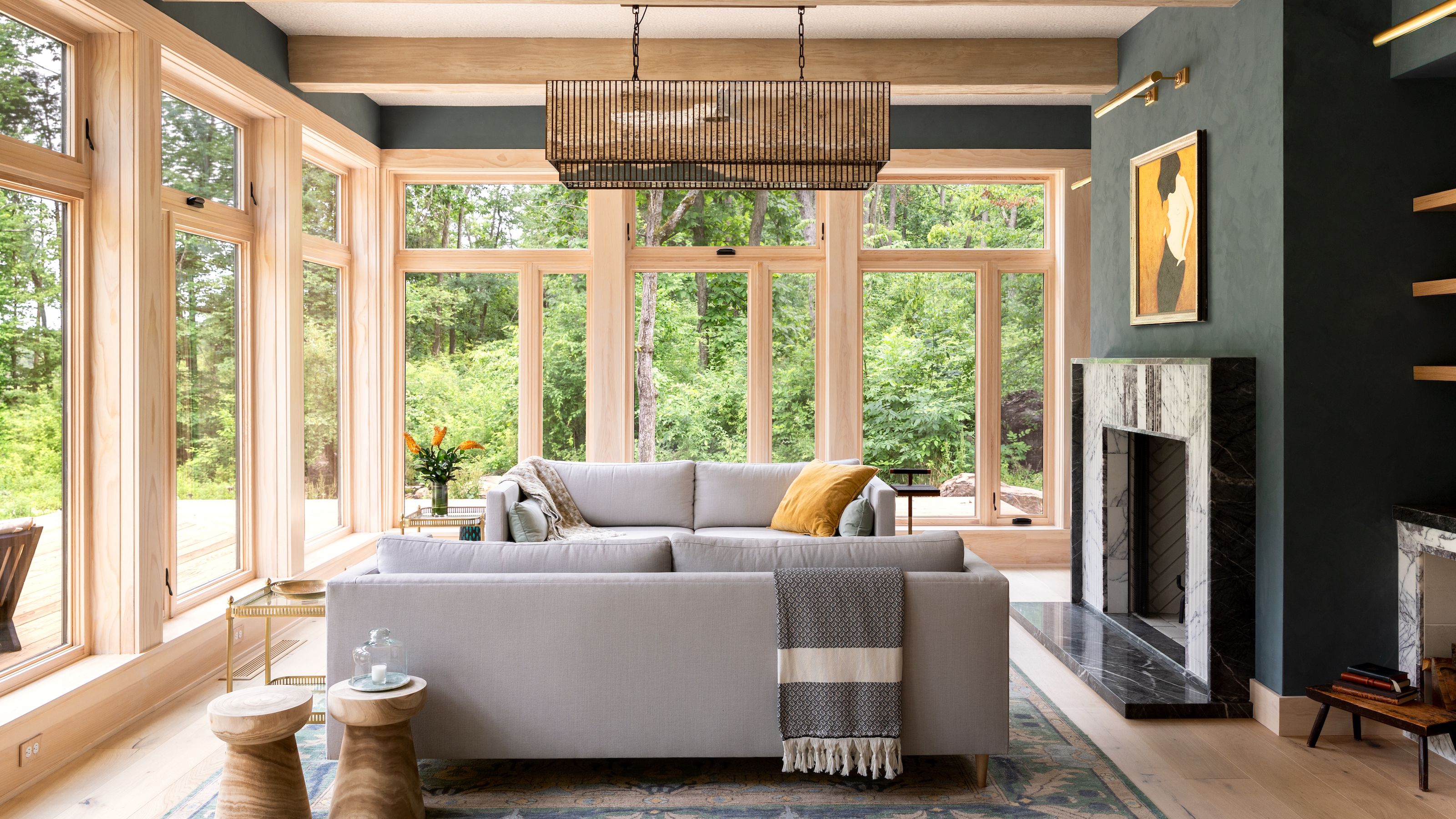 Living room with floor to ceiling windows, fireplace in charcoal colored wall, two facing gray sofas and area rug below