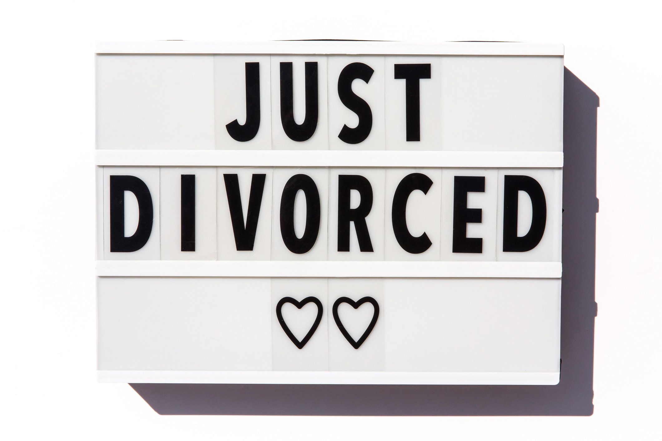 Marriage concept of just divorced sign for happy divorce announcement, relationship difficulties resulting in a breakup, or ex-husband and ex-wife. Short phrase on a letter board on white background. Heart shapes below words. Part of a series.