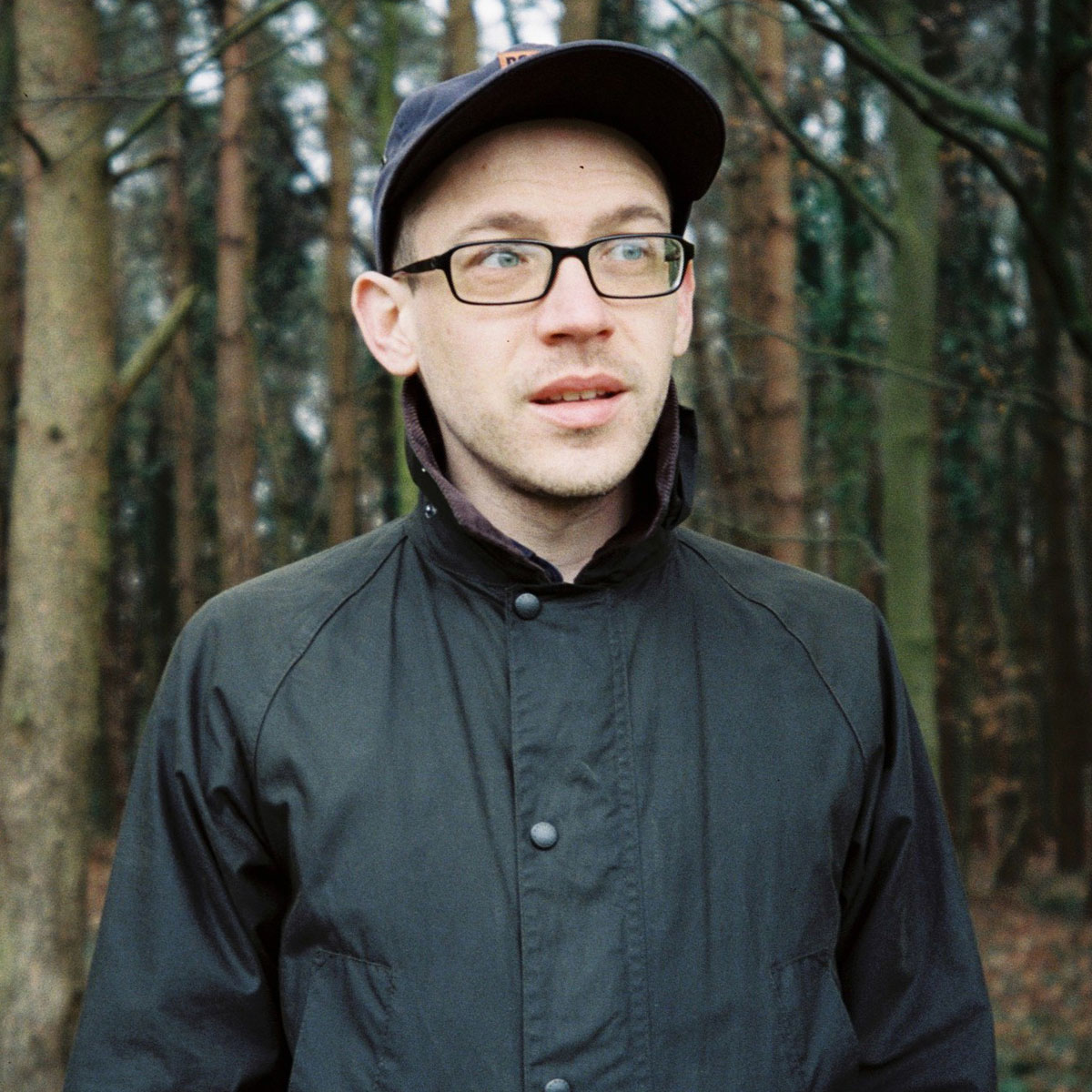 A man wearing a baseball cap in the woods