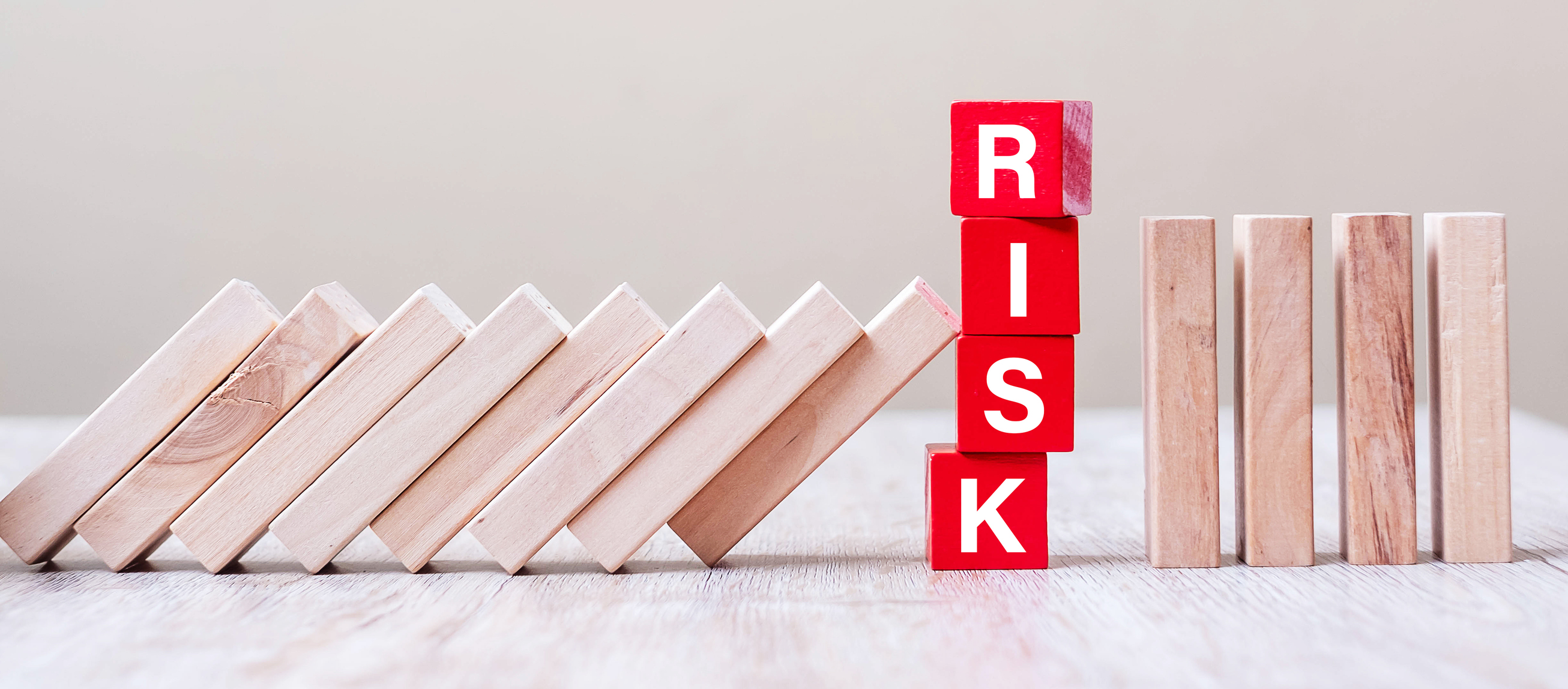 wooden blocks leaning against red letter blocks spelling "risk"
